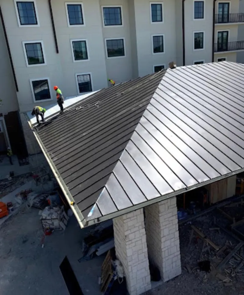 Crew installing standing seam metal roof panels on a commercial project in Newtown